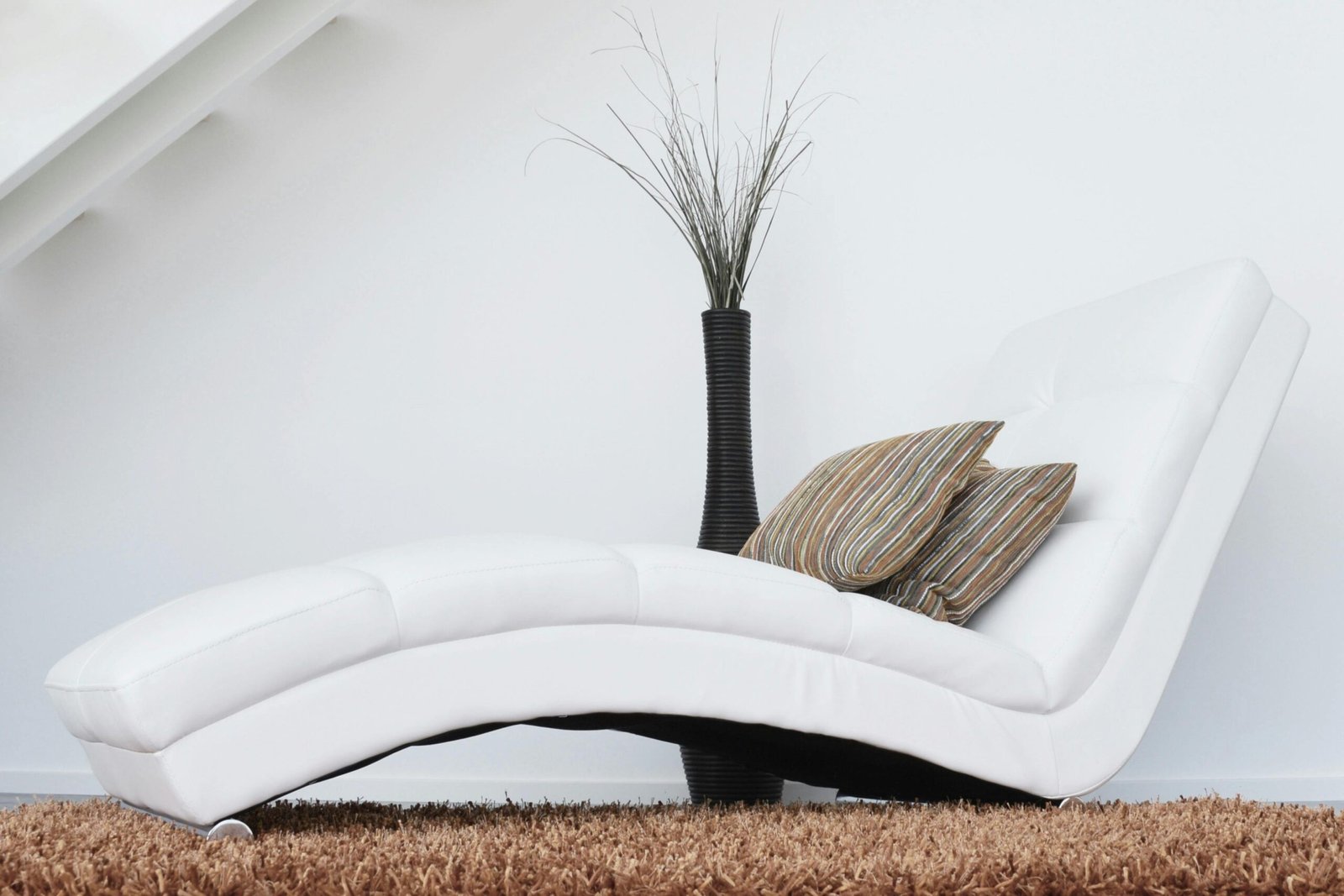 pexels photo 276534 276534 Elegant white lounge chair with cushions on plush carpet, perfect for relaxation.